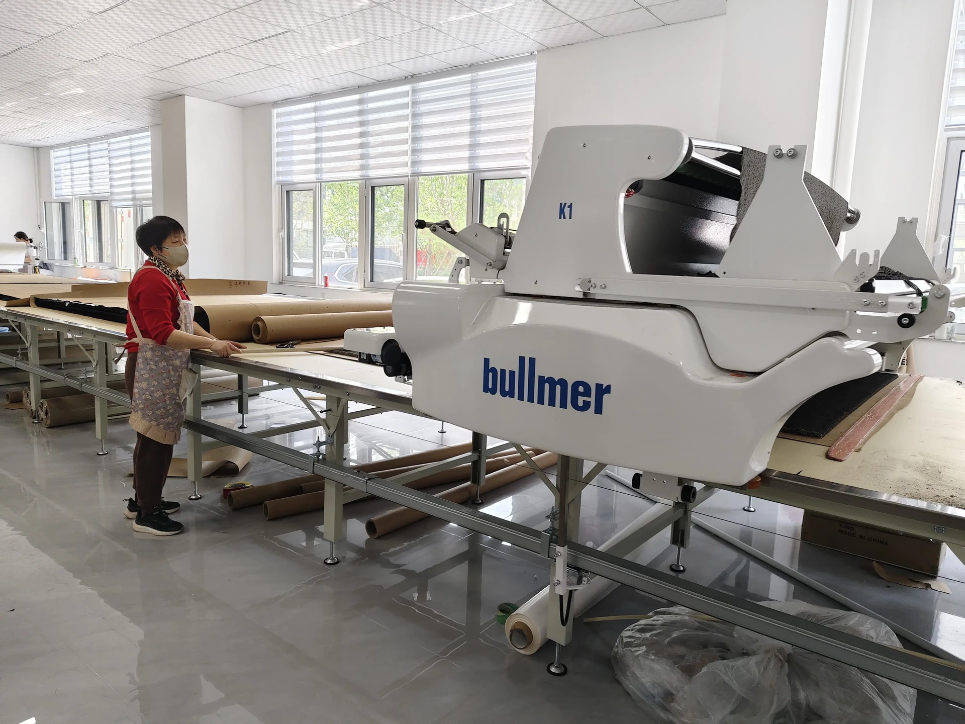 Operator beside a fabric-spreading machine in the workshop