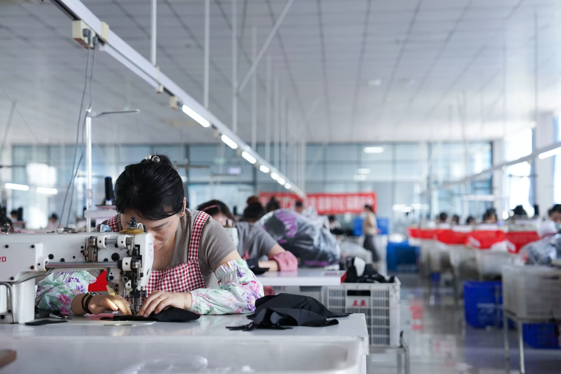 Operator guiding fabric through an industrial sewing machine