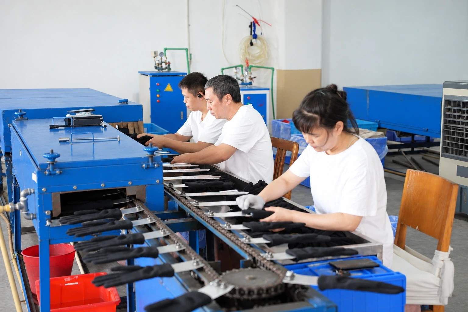 Workers shaping gloves on metal hand forms along a finishing line