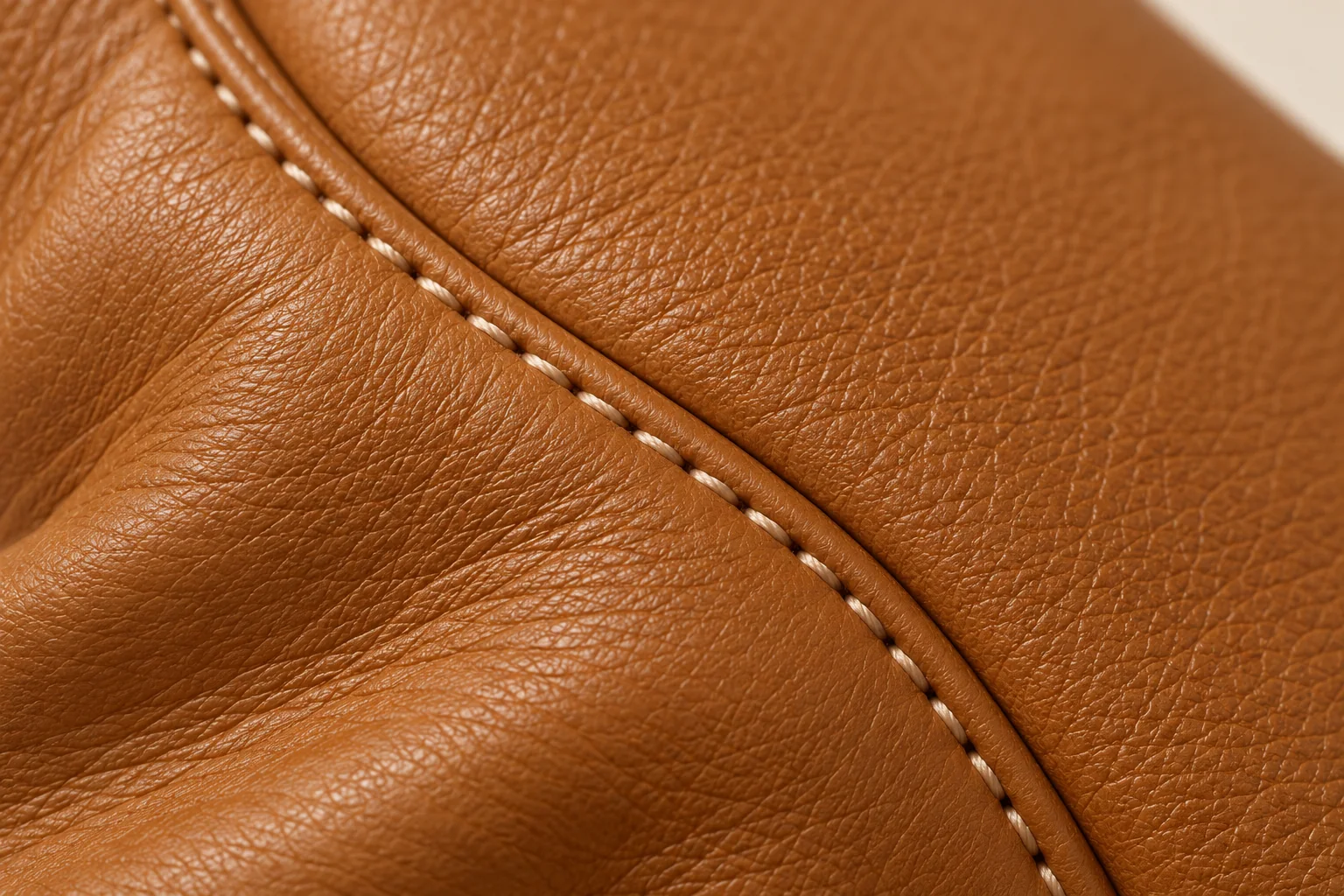 Cream contrast stitching joining cognac leather panels.