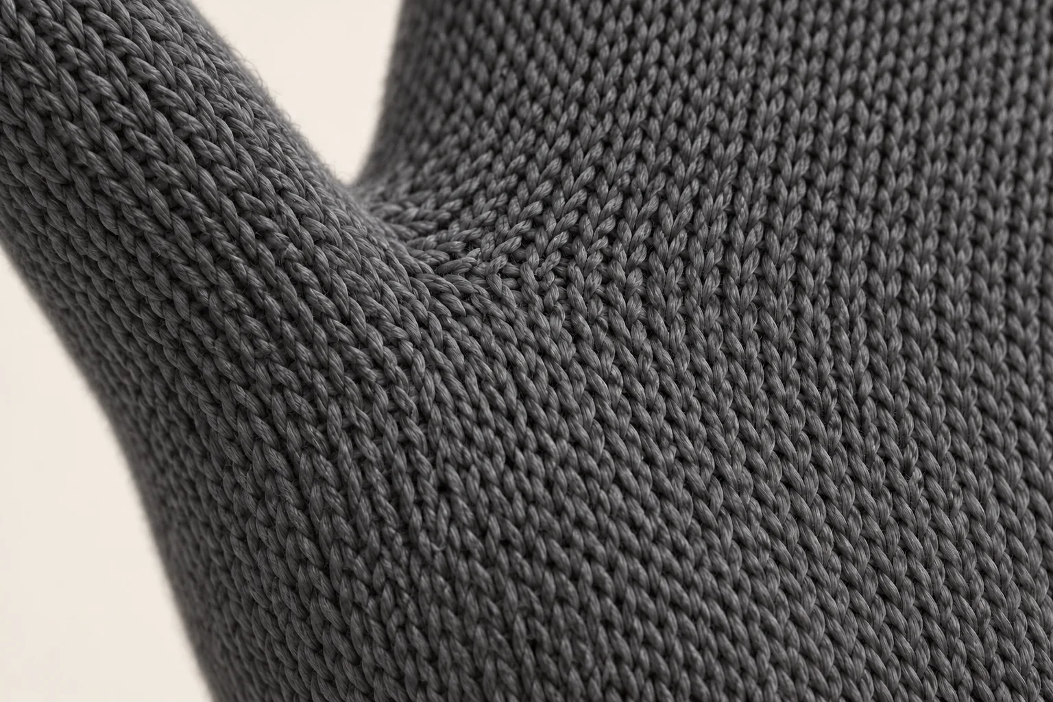 Charcoal plain-knit glove: focus on a small palm-to-thumb gusset junction.
