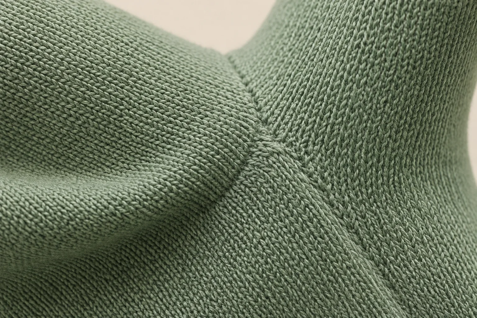 Sage-green fine-knit glove: extreme macro palm-thumb gusset with dense tiny V loops, thin flexible textile shaping, much finer gauge than chunky cream knit.