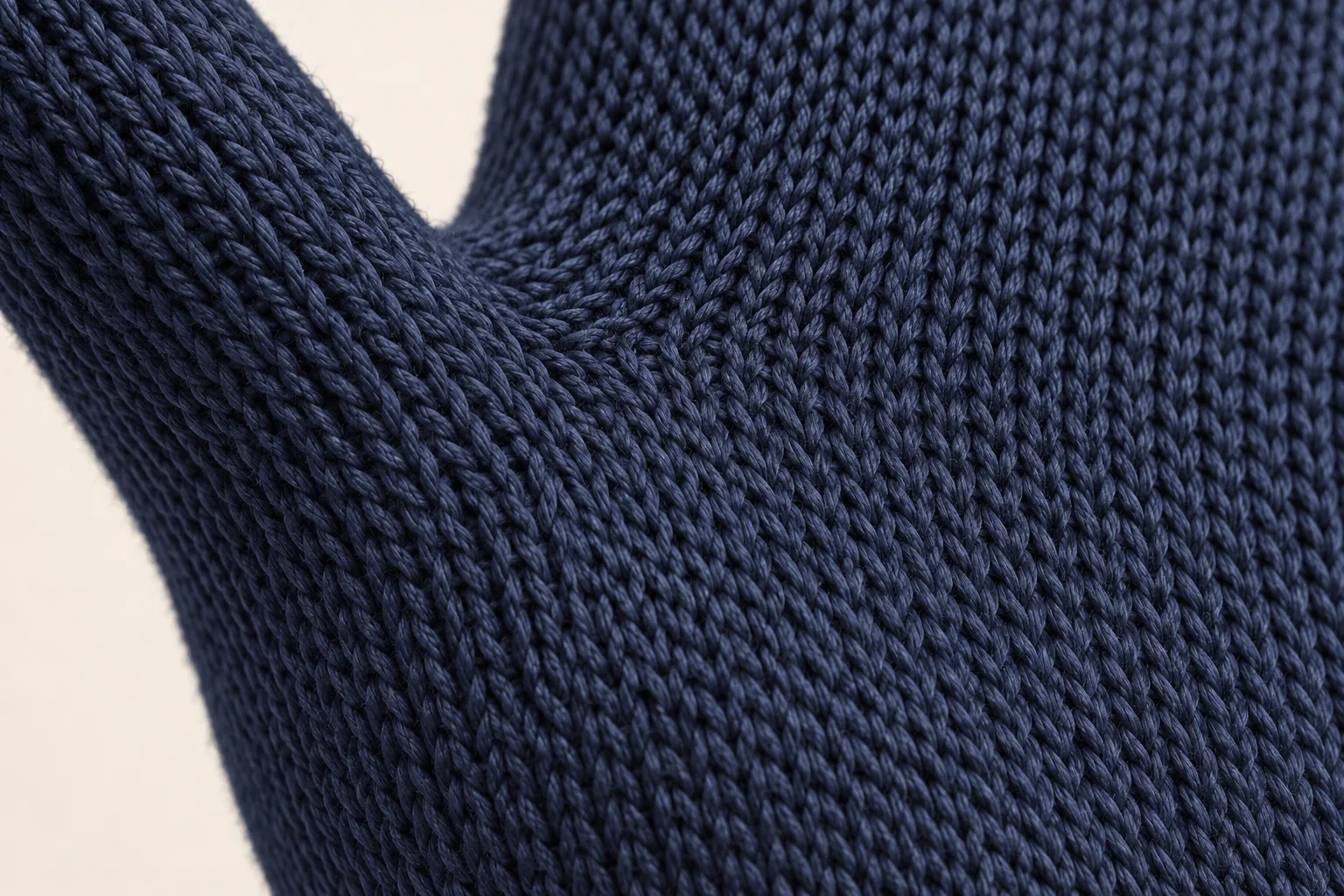 Navy plain-knit glove: small local palm-thumb gusset junction, continuous dark navy V loops changing direction.